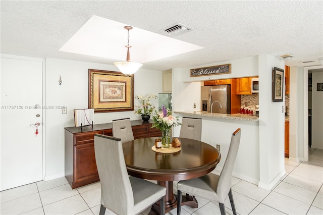 dining area featuring light tile patterned floors, visible vents, and a textured ceiling