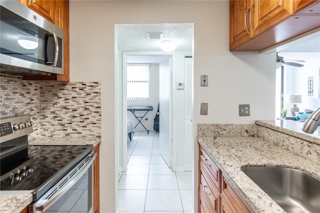 kitchen featuring stainless steel appliances, brown cabinets, a sink, and a textured ceiling