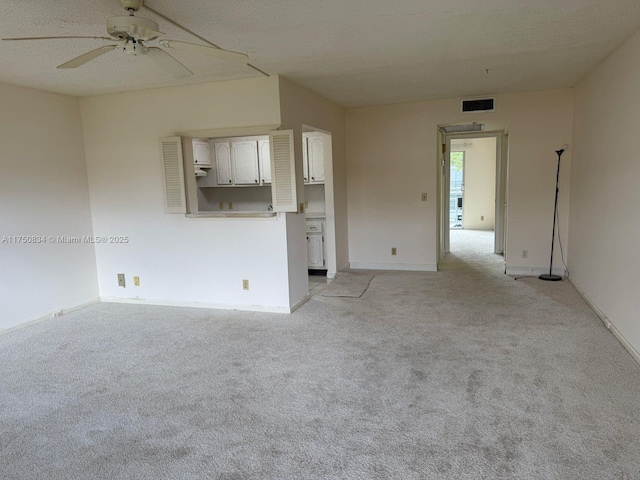 unfurnished living room with visible vents, light carpet, ceiling fan, a textured ceiling, and baseboards