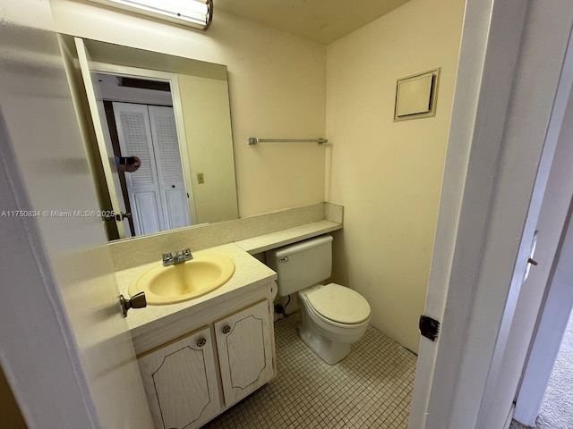 half bath with tile patterned flooring, vanity, and toilet