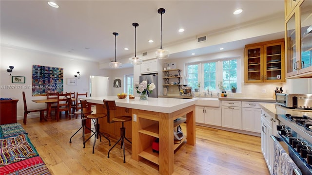 kitchen with open shelves, light countertops, visible vents, freestanding refrigerator, and a sink