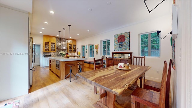 dining room featuring light wood-style floors, baseboards, ornamental molding, and recessed lighting