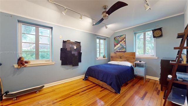 bedroom with hardwood / wood-style flooring, multiple windows, baseboards, and crown molding