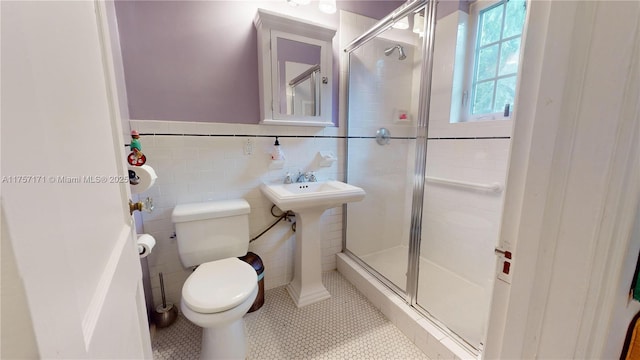 bathroom featuring toilet, a shower stall, tile walls, and tile patterned floors