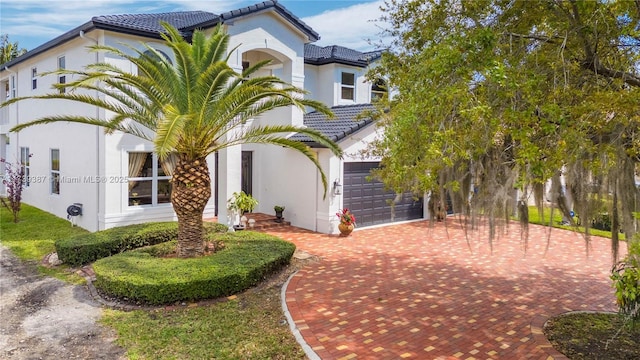 exterior space with stucco siding, a tiled roof, decorative driveway, and a garage