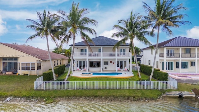 back of house with a yard, a balcony, a fenced backyard, and a water view