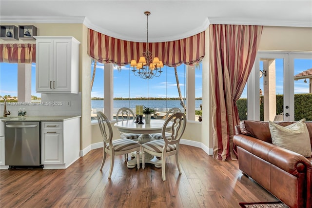 dining room featuring an inviting chandelier, dark wood-style flooring, a wealth of natural light, and ornamental molding