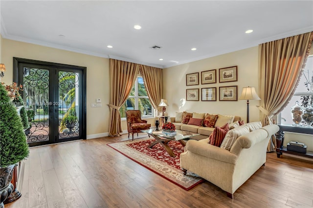 living area featuring french doors, visible vents, hardwood / wood-style floors, and ornamental molding