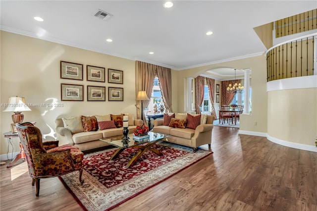 living room with visible vents, a healthy amount of sunlight, crown molding, wood finished floors, and arched walkways