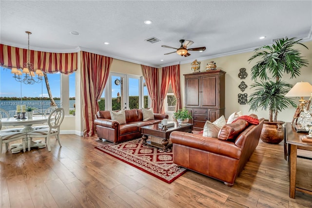 living area with visible vents, a textured ceiling, crown molding, and hardwood / wood-style floors