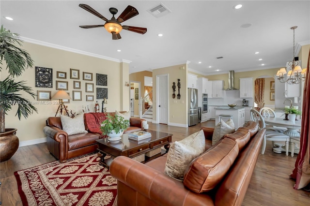 living room with wood finished floors, visible vents, baseboards, arched walkways, and crown molding