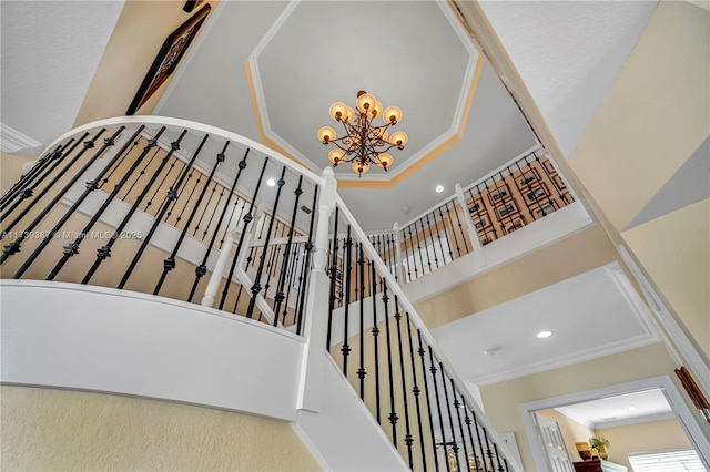 stairs with recessed lighting, crown molding, a towering ceiling, a raised ceiling, and a chandelier