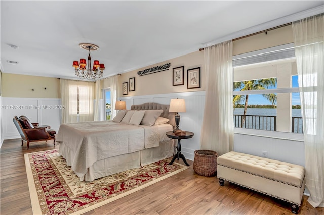 bedroom with visible vents, an inviting chandelier, wood finished floors, and wainscoting