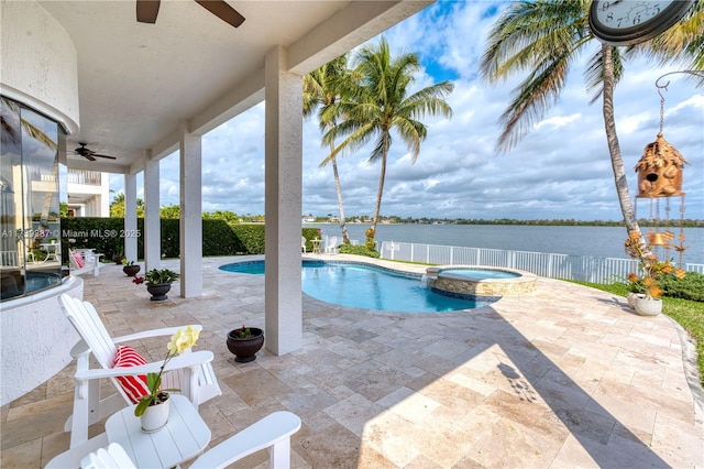 view of pool featuring a patio area, a pool with connected hot tub, ceiling fan, and a water view