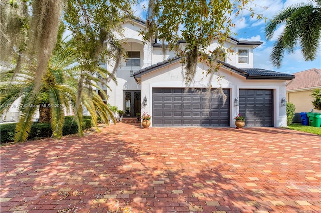 mediterranean / spanish-style house with a tiled roof, decorative driveway, and stucco siding