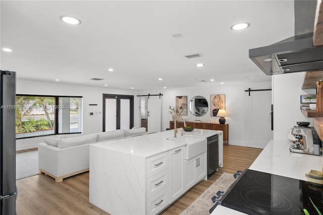 kitchen with exhaust hood, white cabinets, stovetop, and a barn door