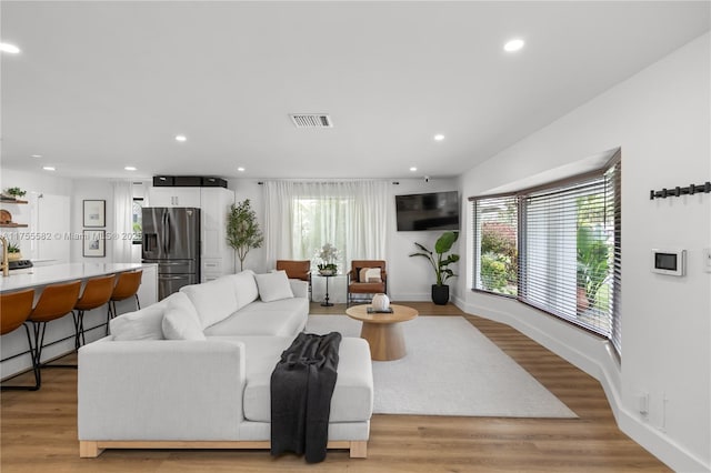 living room featuring light wood-style floors, recessed lighting, visible vents, and baseboards