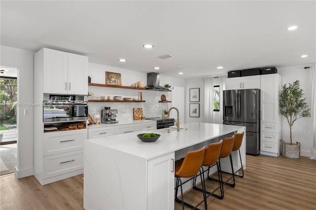 kitchen with a sink, exhaust hood, refrigerator with ice dispenser, light wood-style floors, and open shelves