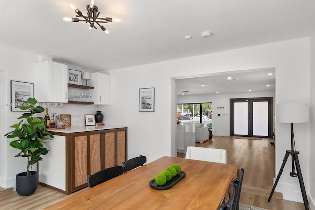 dining area with a chandelier, recessed lighting, baseboards, light wood-style floors, and a bar