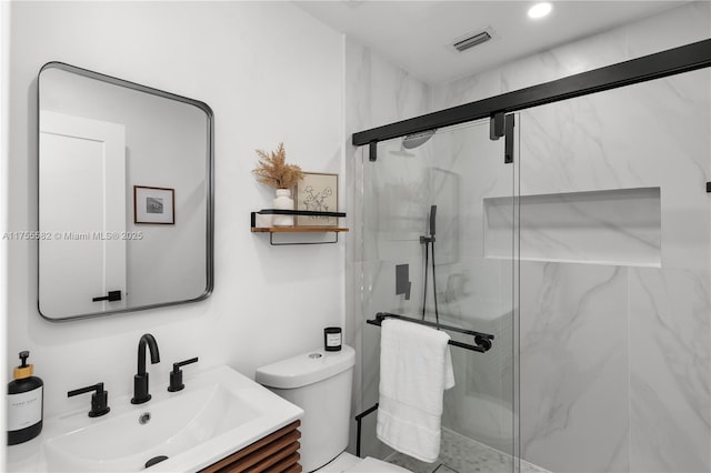 full bath with toilet, vanity, a marble finish shower, and visible vents