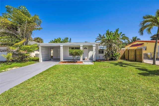 ranch-style house with driveway, an attached carport, fence, a front yard, and stucco siding