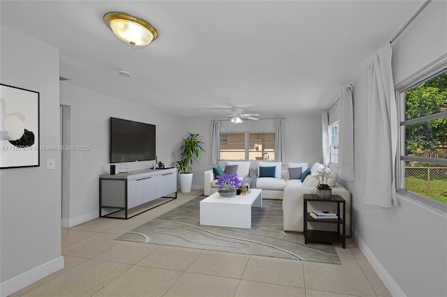 living room with a ceiling fan, light tile patterned flooring, and baseboards