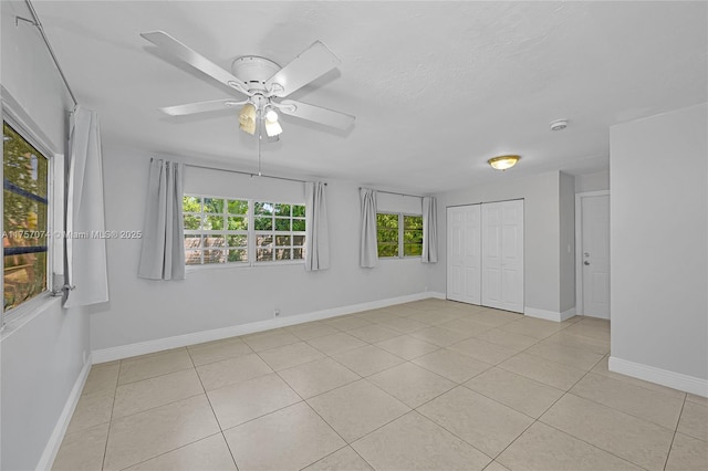 spare room with ceiling fan, a textured ceiling, light tile patterned flooring, and baseboards