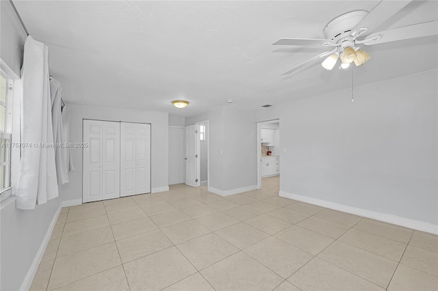 interior space featuring light tile patterned floors, ceiling fan, and baseboards