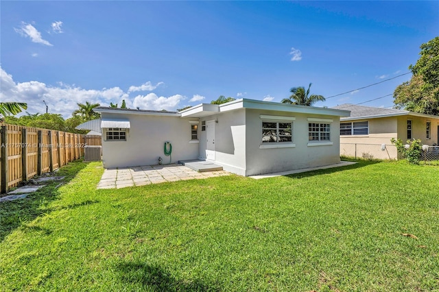 rear view of property featuring a fenced backyard, a lawn, and stucco siding