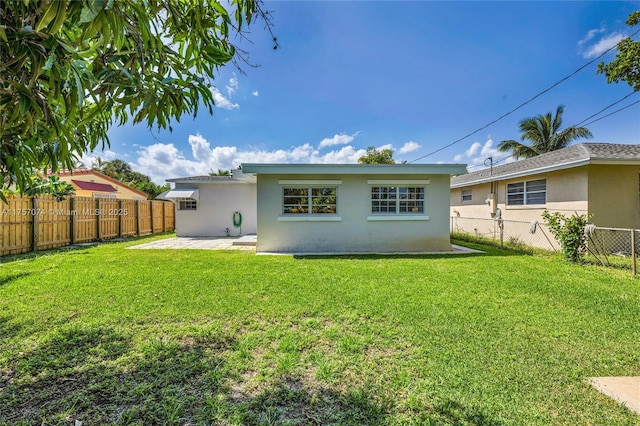 back of house featuring a yard, a fenced backyard, and stucco siding