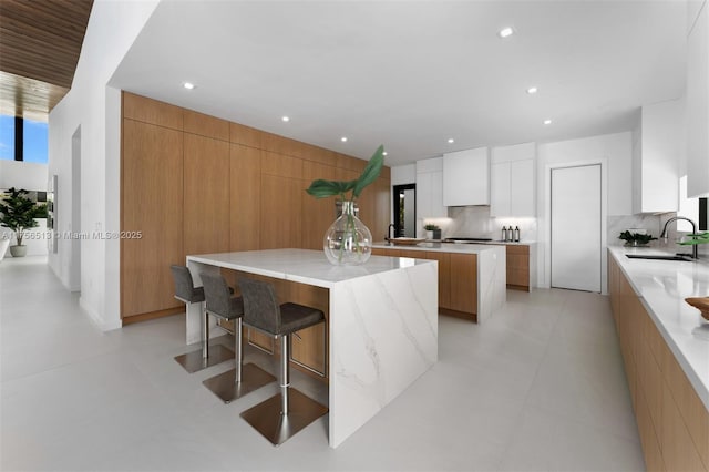 6991 SW 91st St, Pinecrest, FL 33156 - kitchen featuring modern cabinets, a large island, tasteful backsplash, light stone countertops, and a breakfast bar