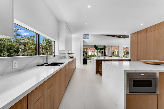 6991 SW 91st St, Pinecrest, FL 33156 - kitchen featuring modern cabinets, oven, light stone countertops, recessed lighting, and tasteful backsplash