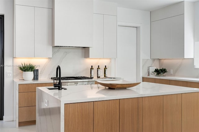 6991 SW 91st St, Pinecrest, FL 33156 - kitchen featuring modern cabinets, backsplash, light stone countertops, and a center island
