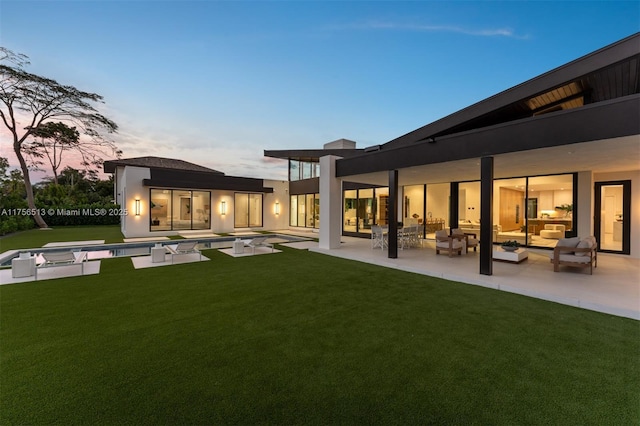 6991 SW 91st St, Pinecrest, FL 33156 - back of property at dusk with an outdoor living space, a patio area, and a lawn