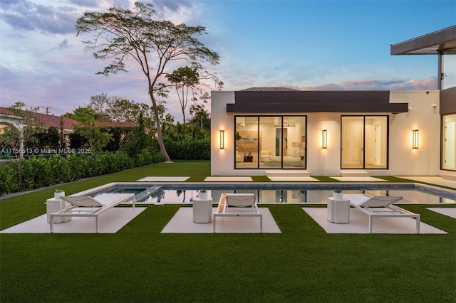 6991 SW 91st St, Pinecrest, FL 33156 - back of house with a patio area, an outdoor pool, a lawn, and stucco siding