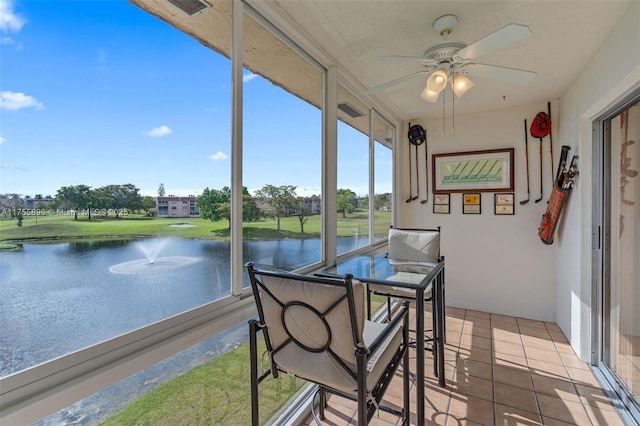 sunroom featuring a water view and a ceiling fan