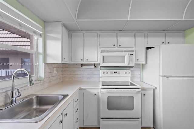 kitchen featuring light countertops, white appliances, a sink, and white cabinetry