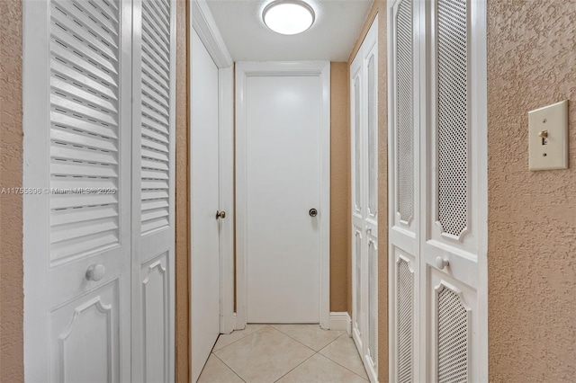 corridor featuring a textured wall and light tile patterned floors