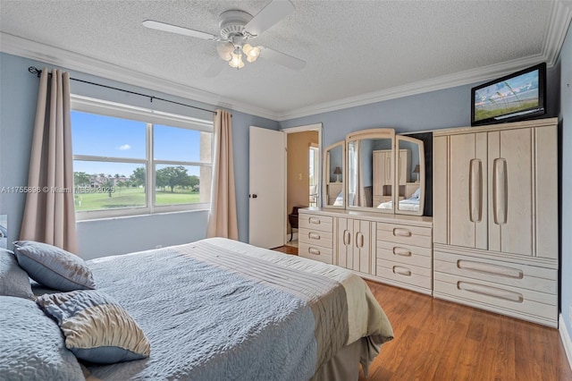 bedroom with a textured ceiling, ceiling fan, ornamental molding, and wood finished floors