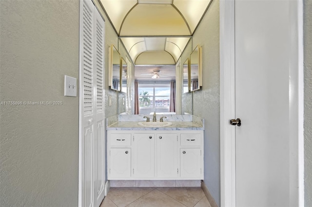 bathroom featuring tile patterned flooring, a textured wall, and vanity