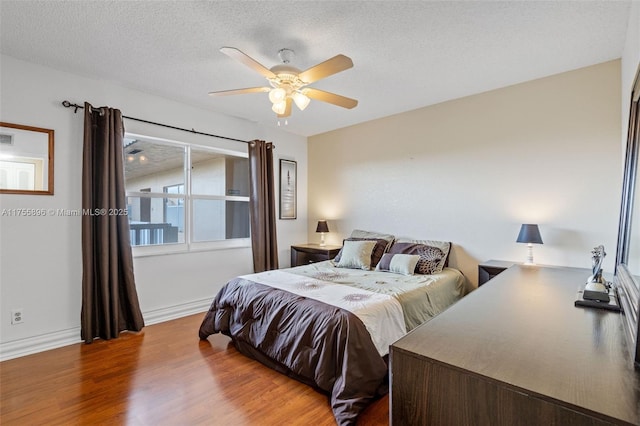 bedroom with baseboards, a textured ceiling, a ceiling fan, and wood finished floors