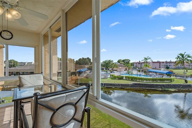 sunroom with a water view and ceiling fan