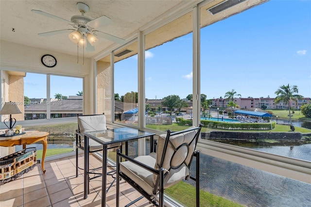 sunroom / solarium featuring a water view and a ceiling fan