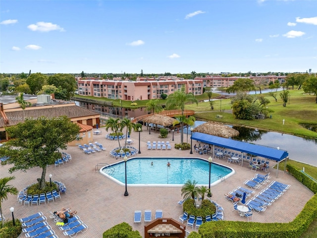 community pool with cooling unit, a water view, and a patio