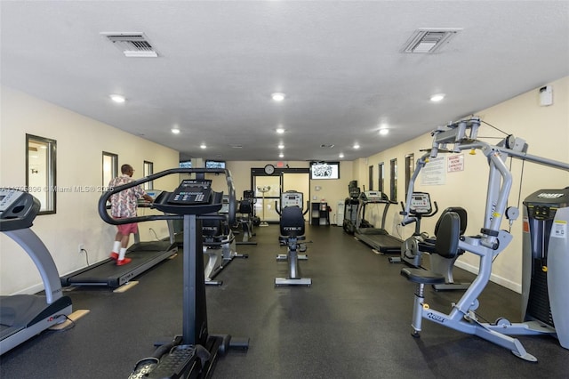 exercise room with baseboards, visible vents, and a textured ceiling