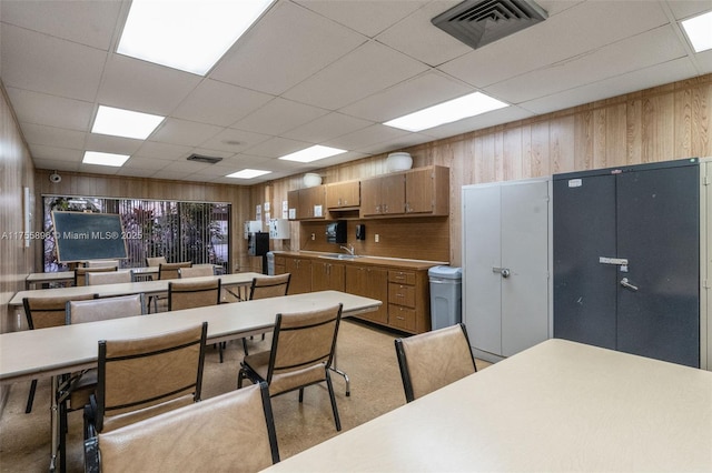 kitchen featuring wood walls, brown cabinetry, a sink, and visible vents