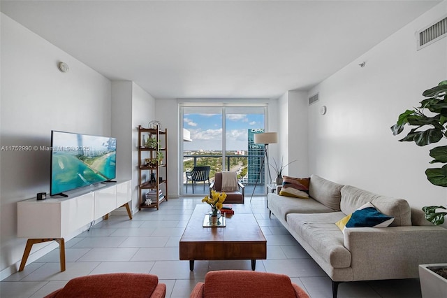 tiled living area with baseboards, visible vents, and a wall of windows