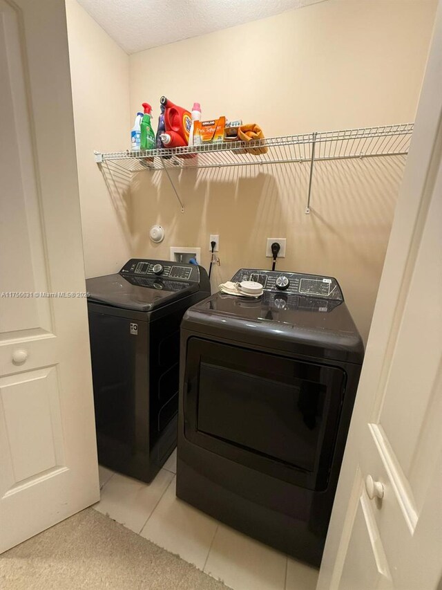 laundry area with laundry area, light tile patterned flooring, a textured ceiling, and independent washer and dryer