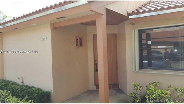 property entrance with a tiled roof and stucco siding