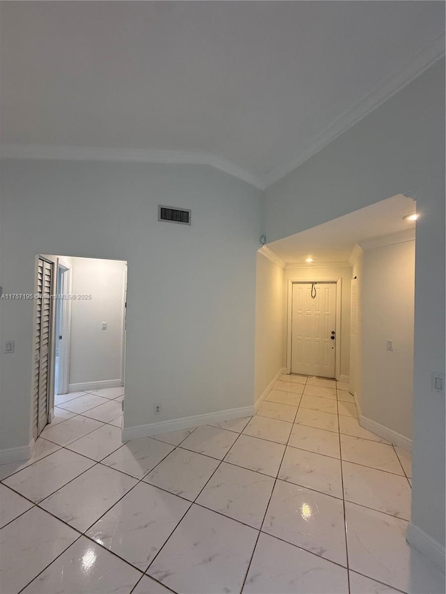 spare room with crown molding, lofted ceiling, visible vents, light tile patterned flooring, and baseboards